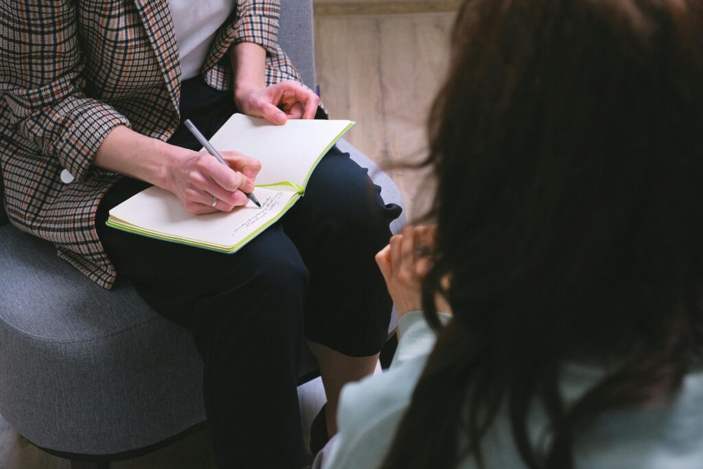 A close-up of a therapy session with a notepad, encapsulating professional dialogue and note-taking.